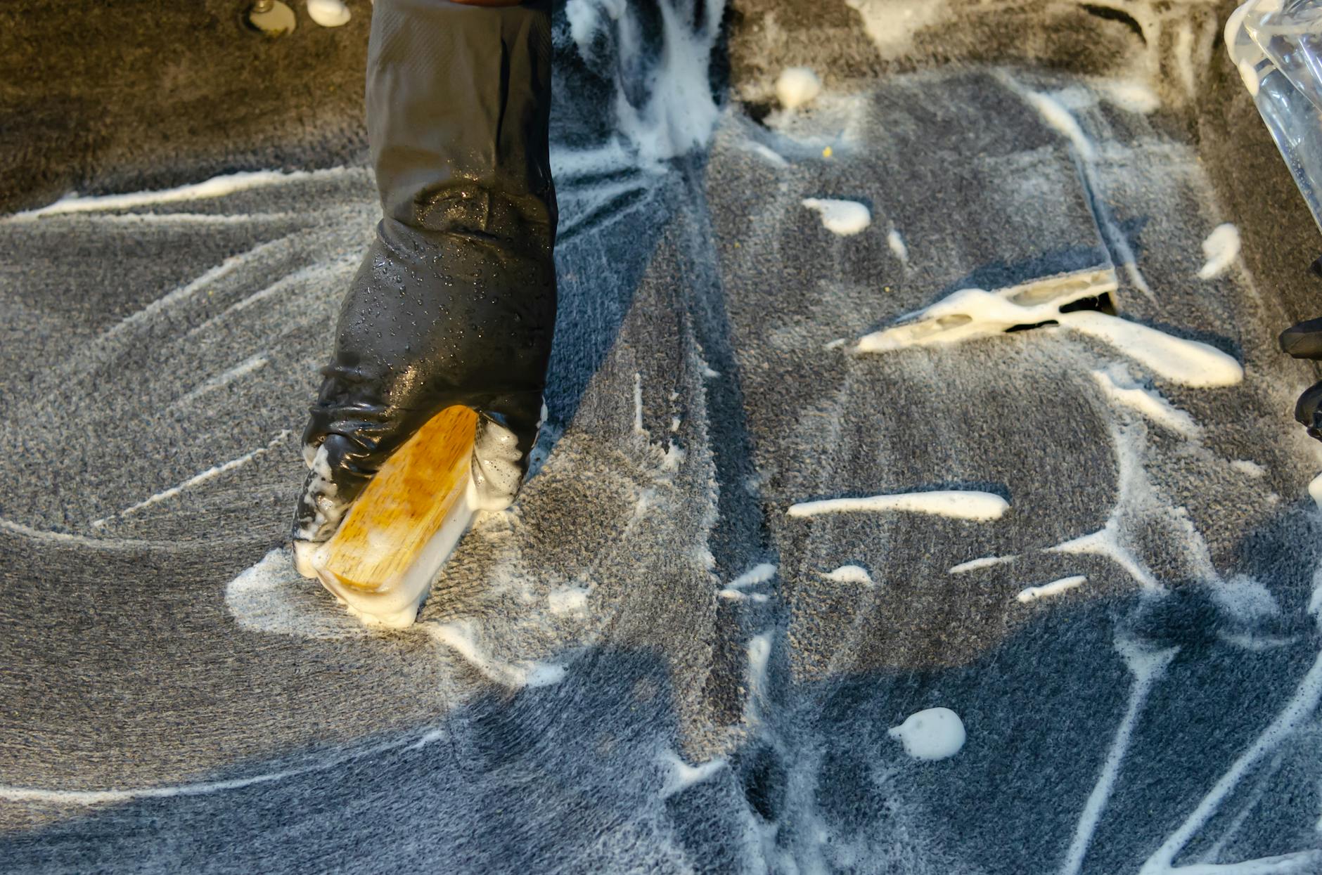 Proper Carpet Stain Scrubbing Technique Gloved hand using a brush with detergent to scrub a stain — demonstrating proper cleaning technique
