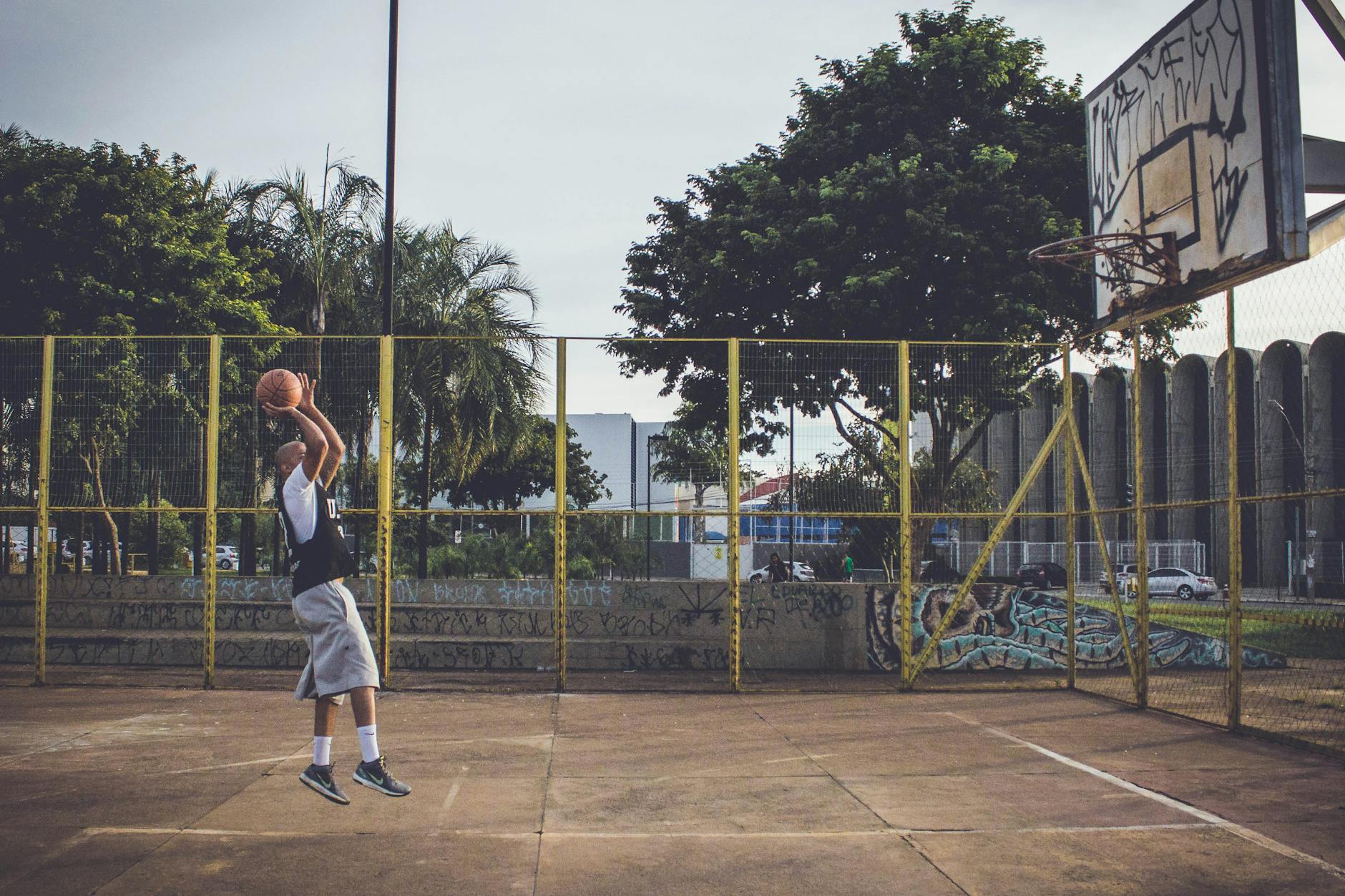 Basketball Player Jumping in Athletic Shoes Basketball player jumping on an outdoor urban court wearing athletic shoes