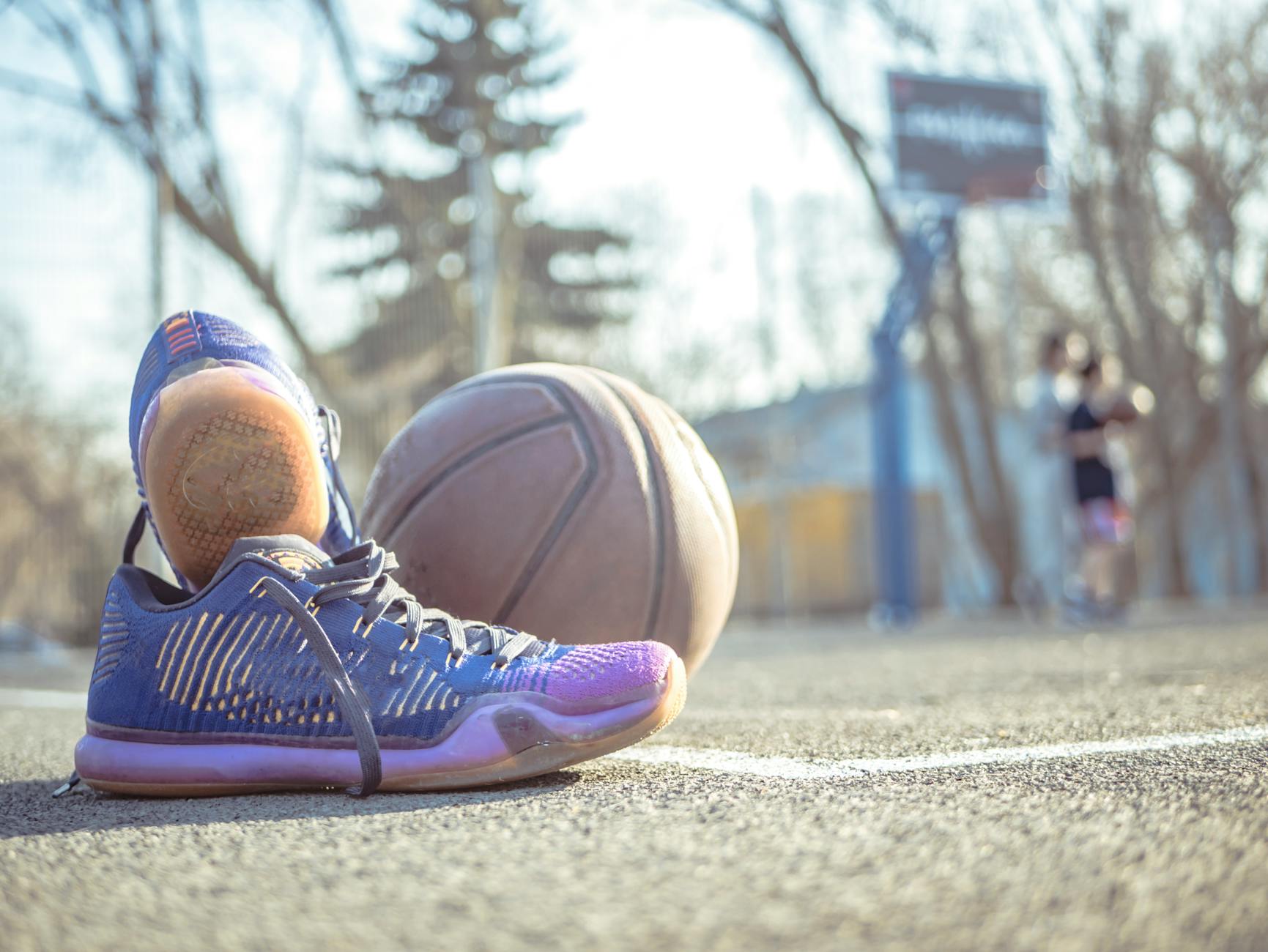 Sneakers and Basketball on Outdoor Court Sneakers placed next to a basketball on an outdoor court