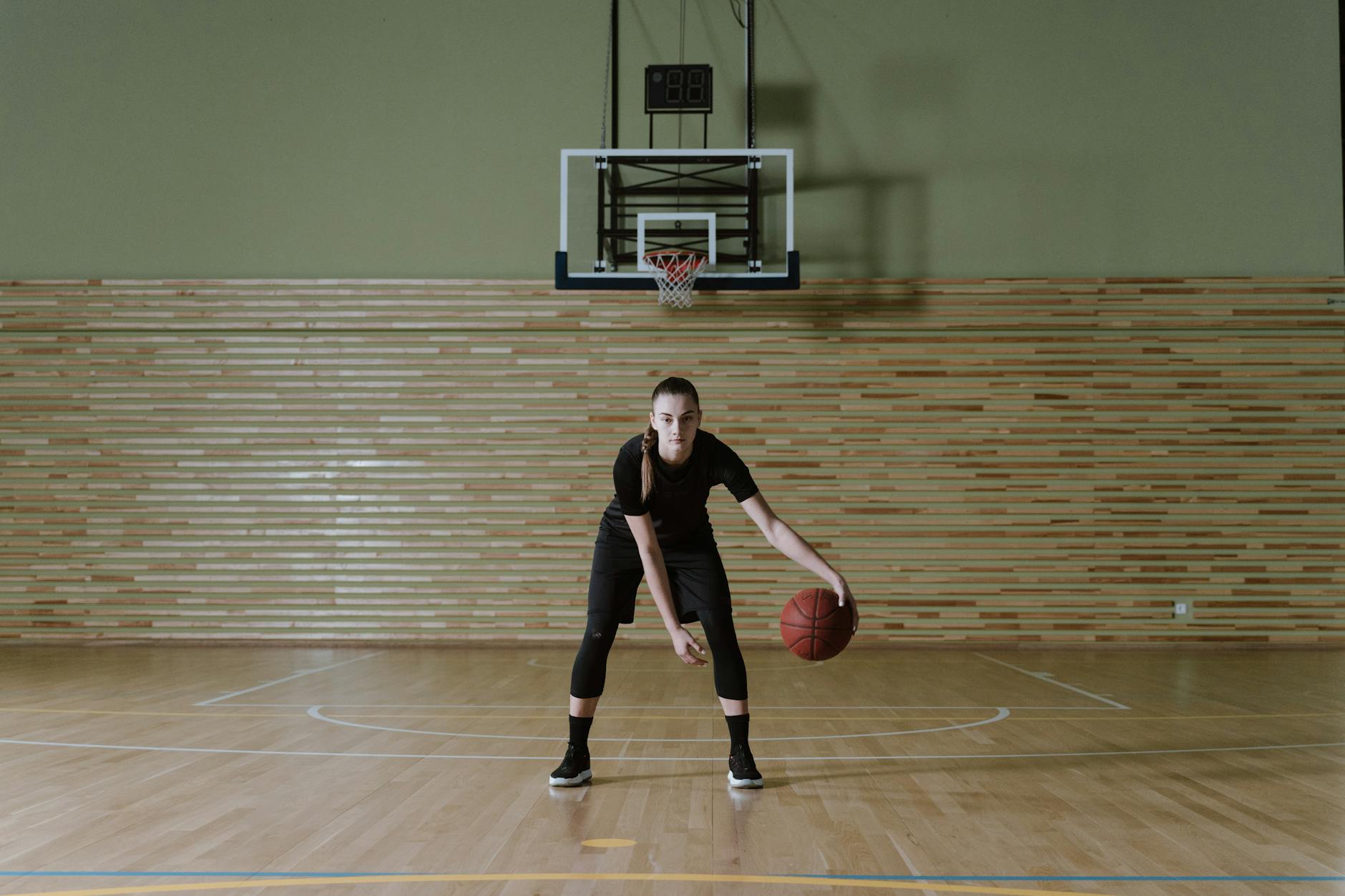 Solo Basketball Practice Drills Indoor Woman focused on dribbling basketball in an indoor training setting