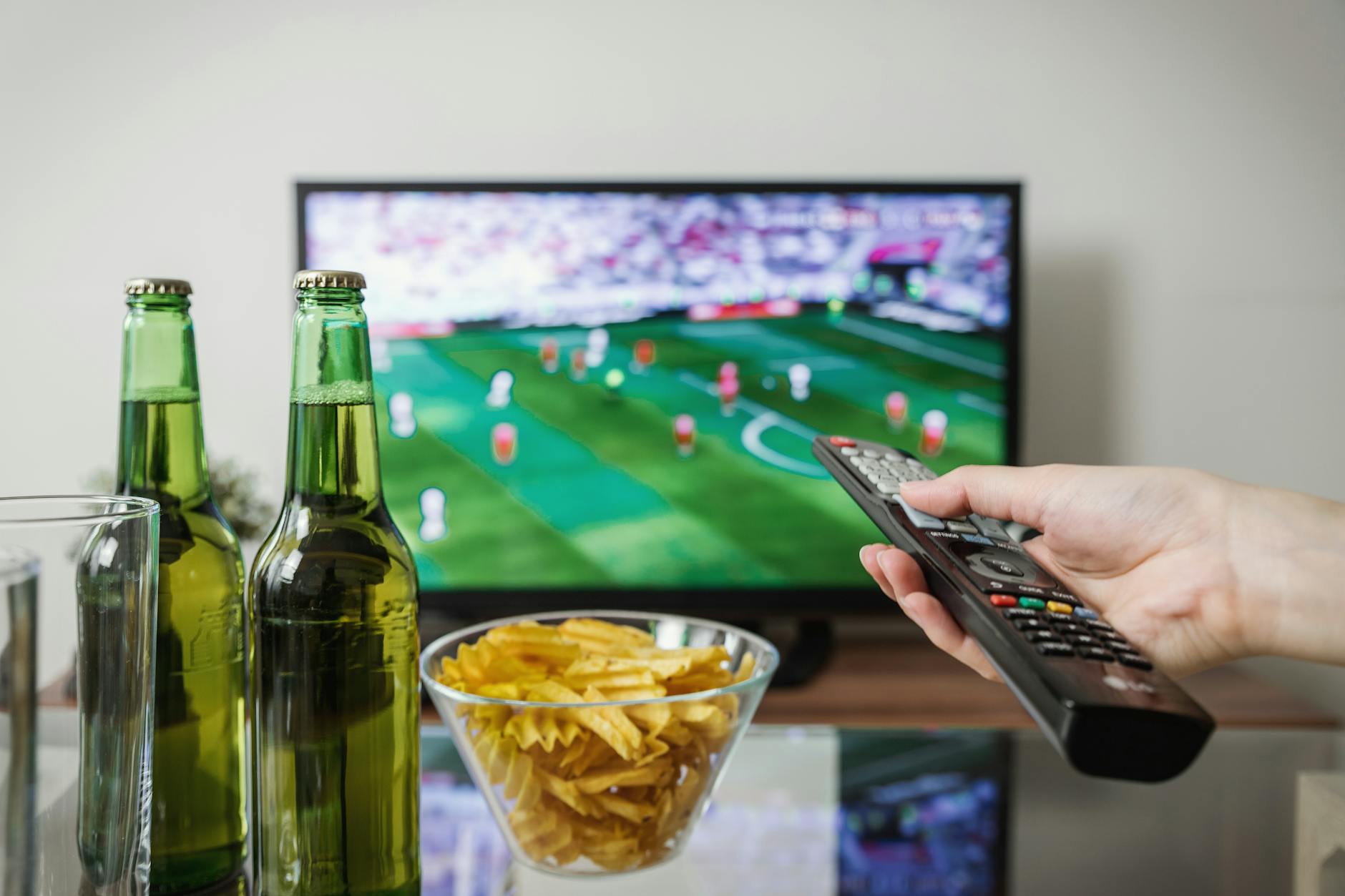 NBA Game Day Home Viewing Setup 2026 Person watching sports on TV with snacks and remote — classic NBA game day setup