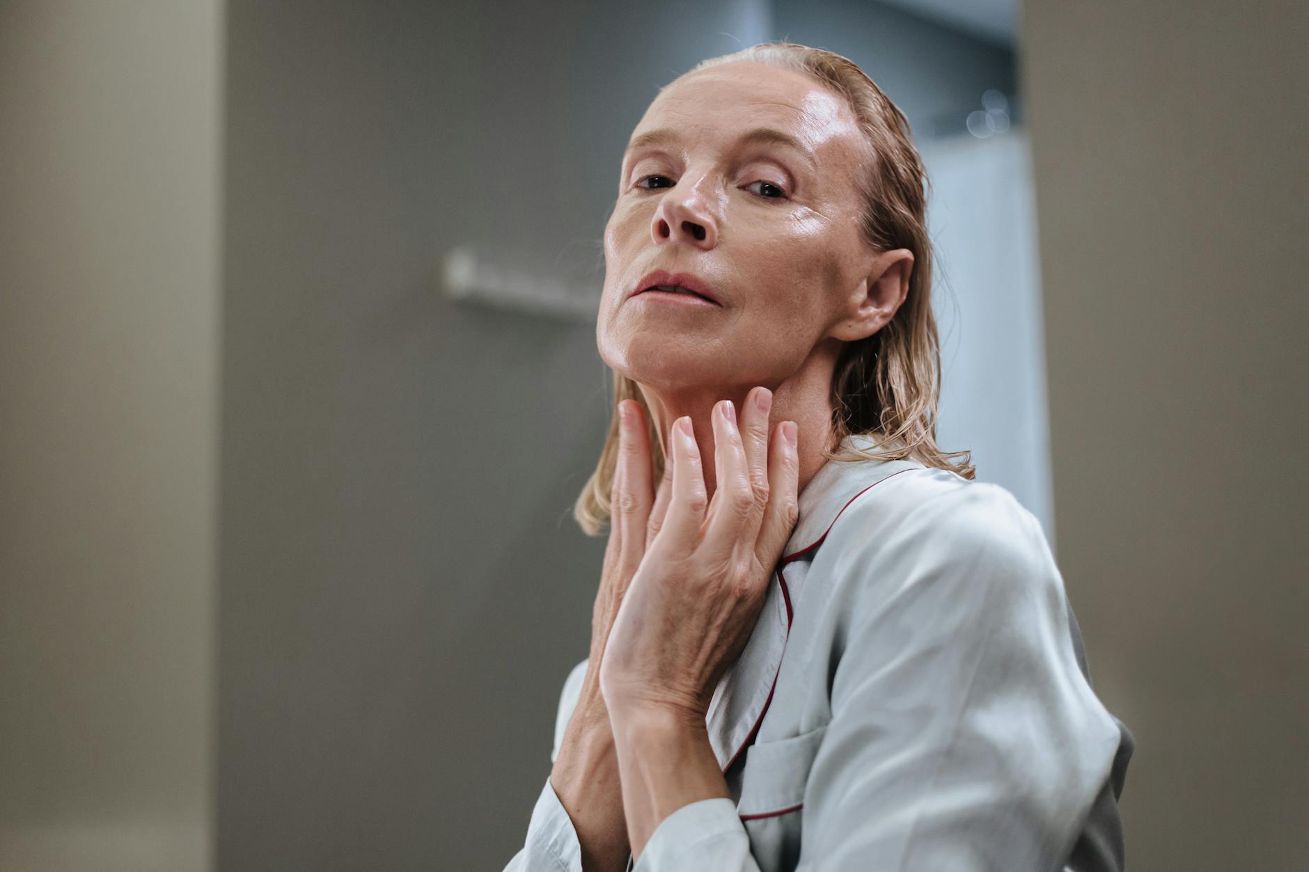 Mature Woman Skincare Facial Hair Aging Mature woman applying skincare product in a bathroom — managing facial hair changes with age