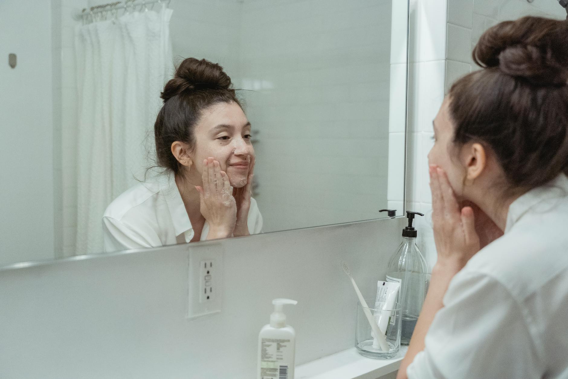 Woman Skincare Routine Mirror Bathroom Woman examining her face in a bathroom mirror during a skincare routine