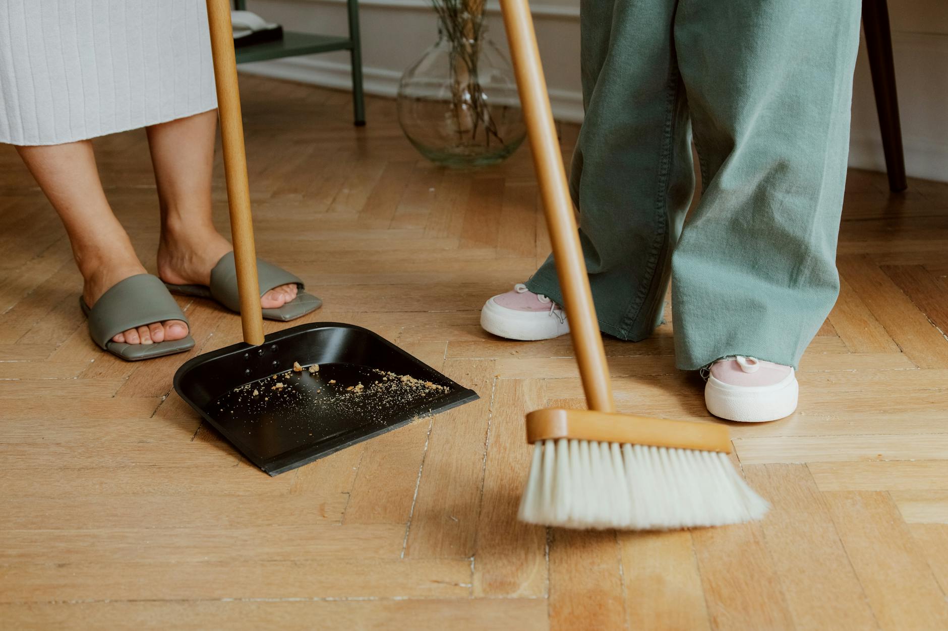 Sweep or Vacuum Before Mopping — How to Clean Floors Properly Person sweeping wooden floor with broom and dustpan before mopping — proper floor cleaning order