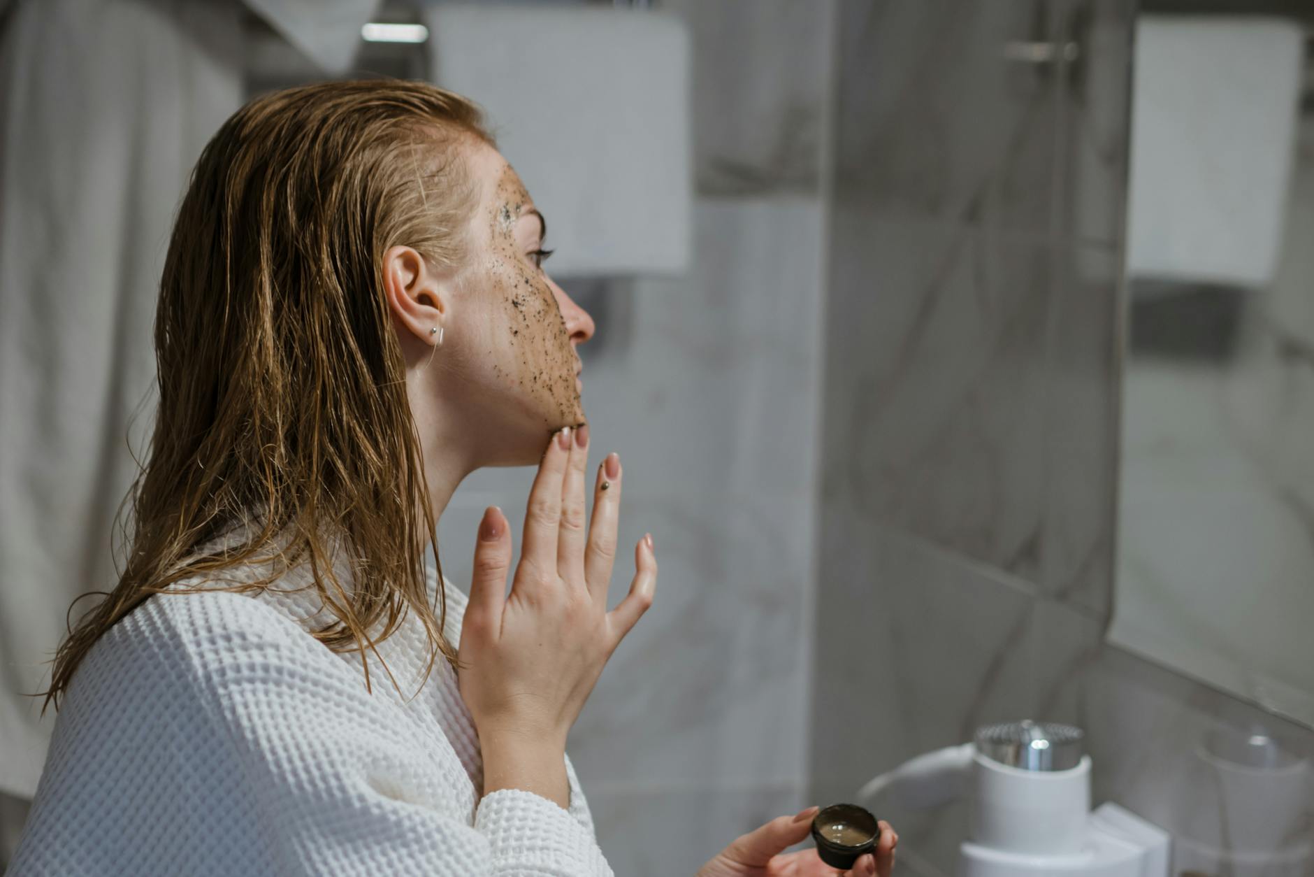 At-Home Facial Exfoliation and Skincare Routine Woman applying facial scrub exfoliation treatment at home in bathroom