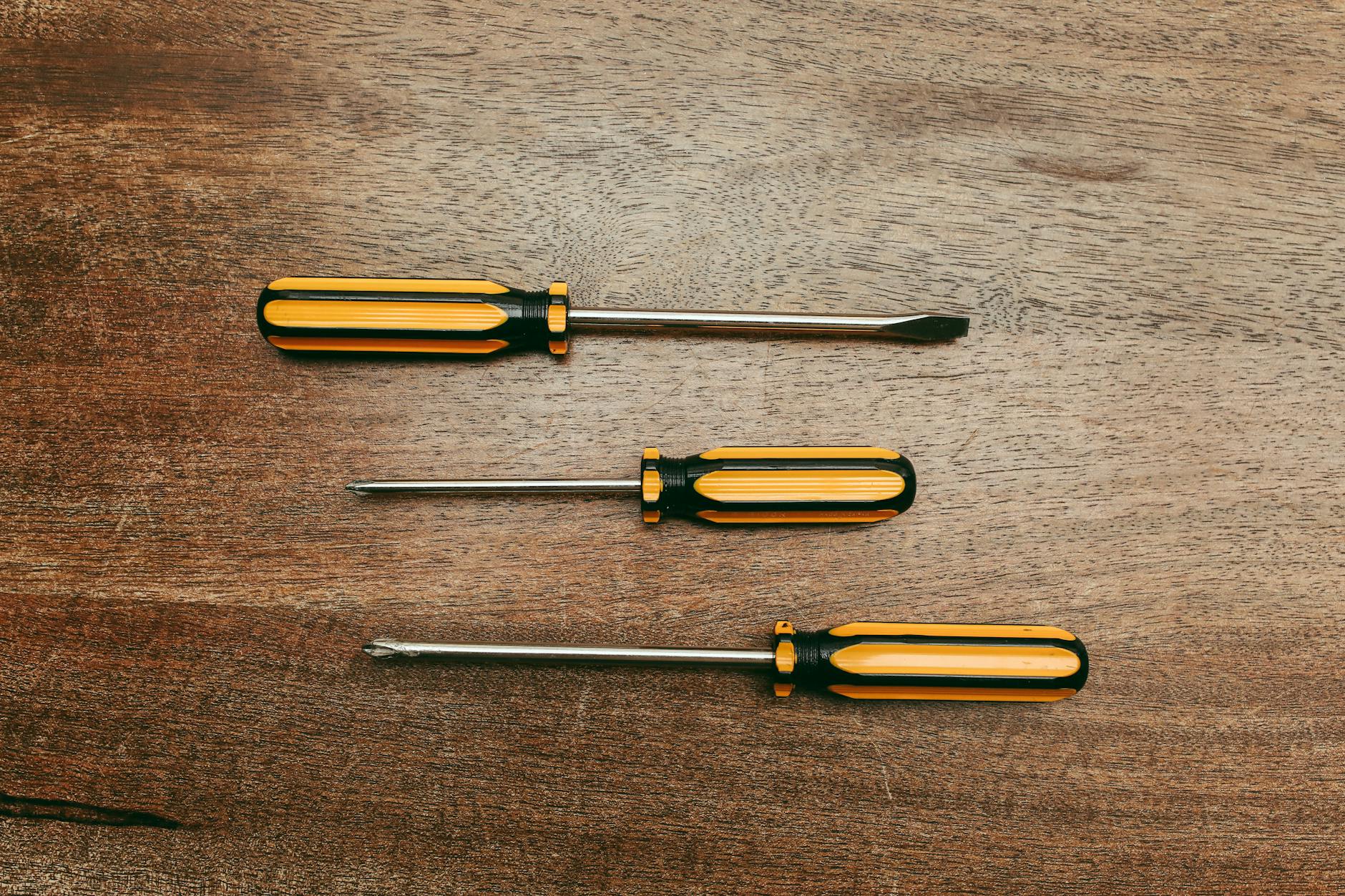 Screwdrivers for Simple Home Repairs 2026 Three screwdrivers laid flat on a wooden table for simple home repairs