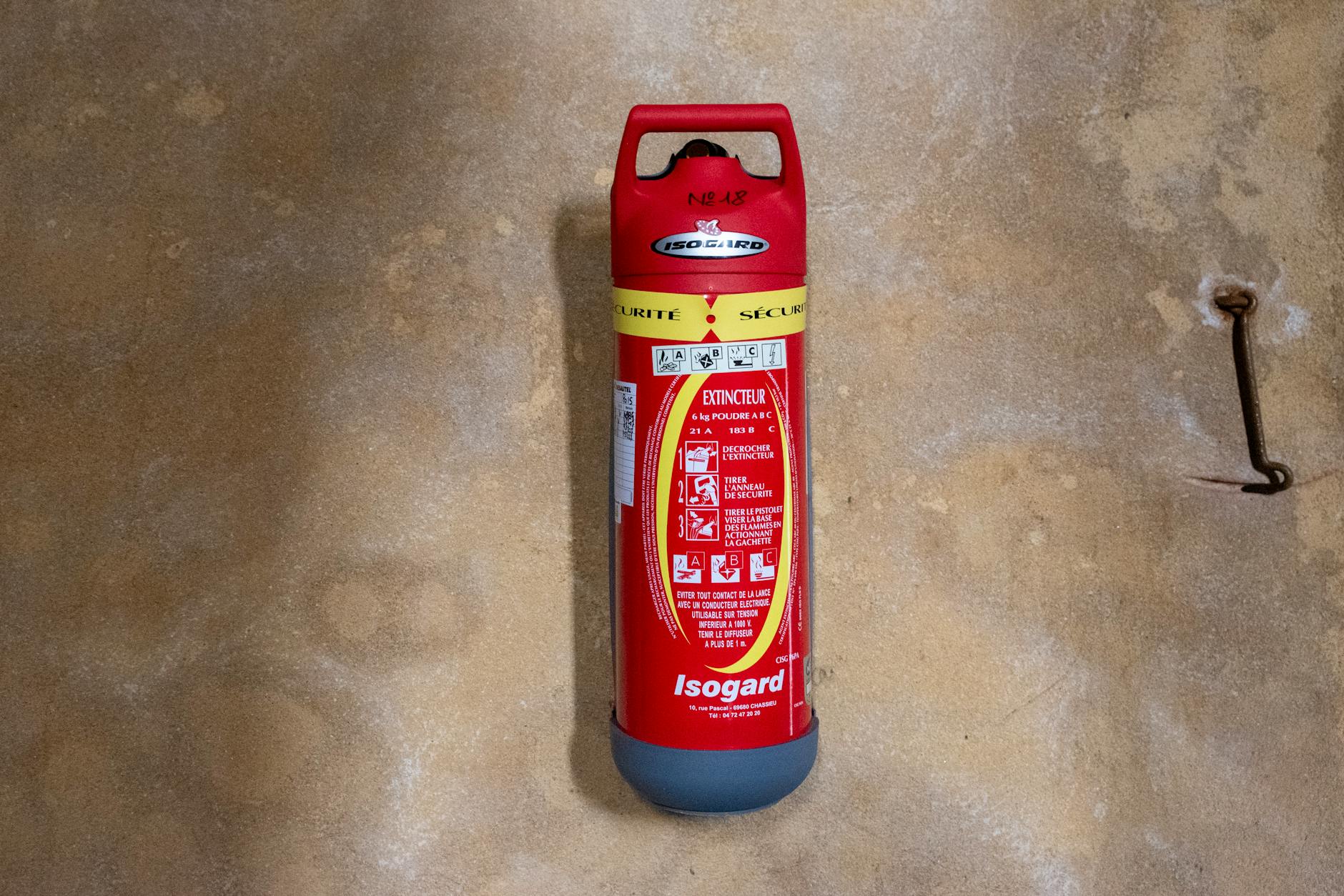 Proper Fire Extinguisher Mounting — Home Safety Red Isogard fire extinguisher properly mounted on a textured wall ready for use
