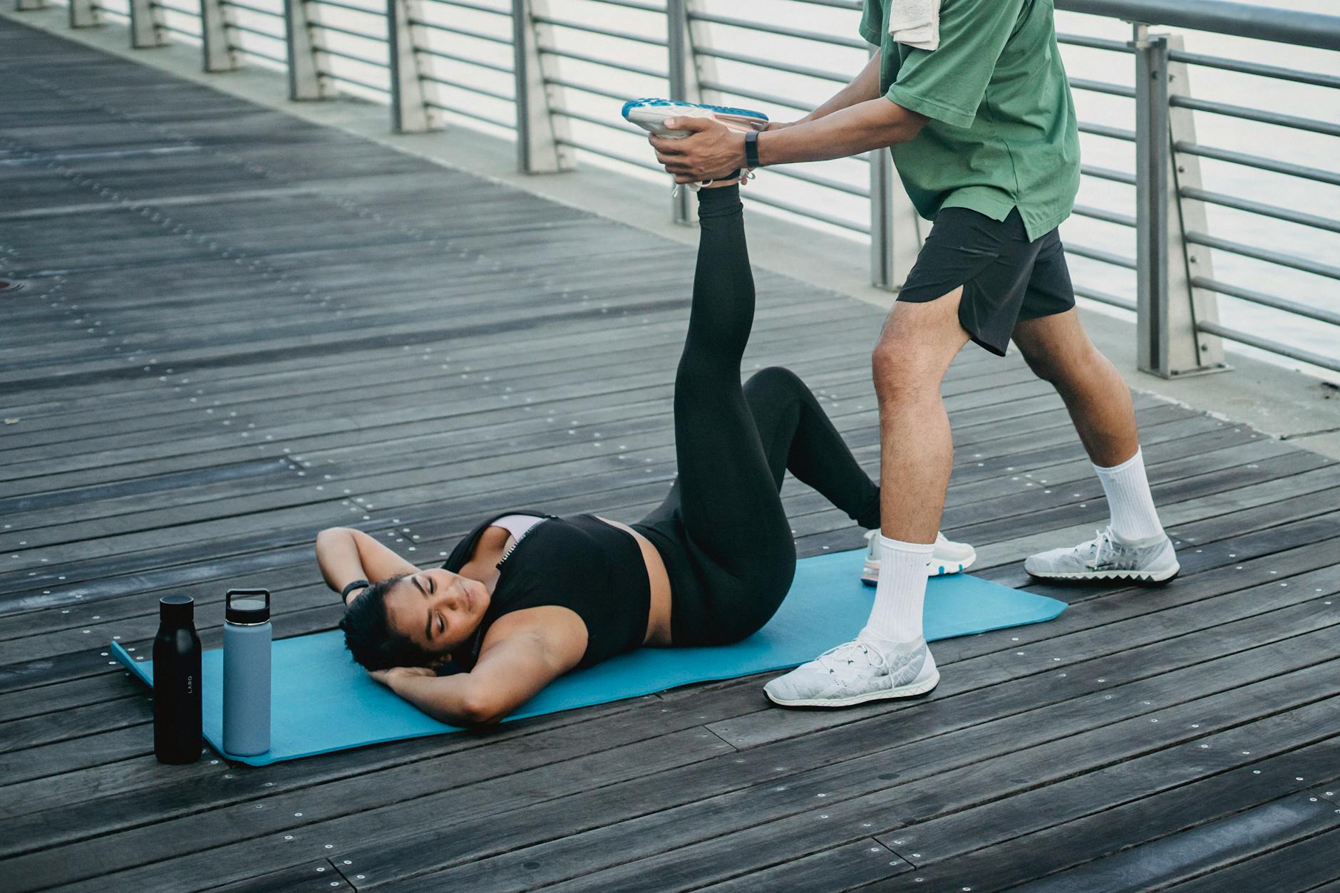 Daily Flexibility Routine for Golfers Trainer assisting a woman with a flexibility stretch outdoors — guided mobility work improves golf performance