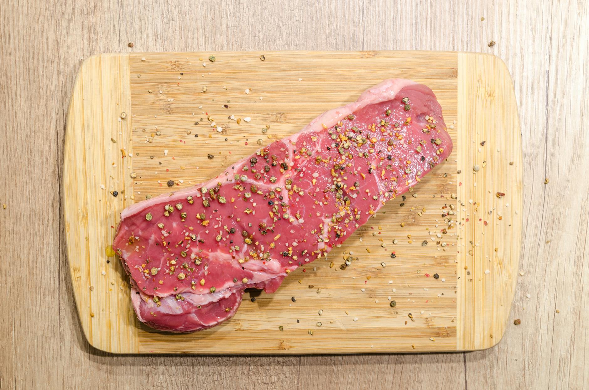 Raw Meat on Cutting Board - Cross-Contamination Risk Raw beef steak on a wooden cutting board illustrating cutting board cross contamination risk