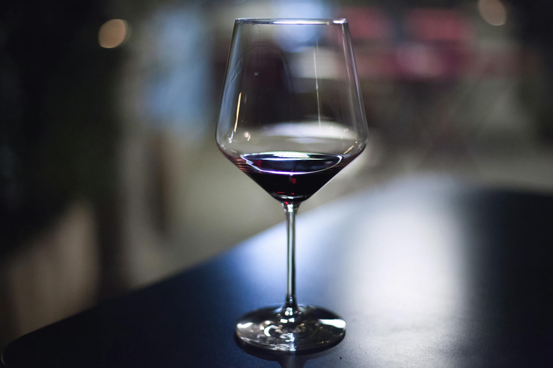 Red Wine Tooth Staining Explained A glass of red wine on a dark table — red wine's tannins and anthocyanins make it one of the worst drinks for tooth staining