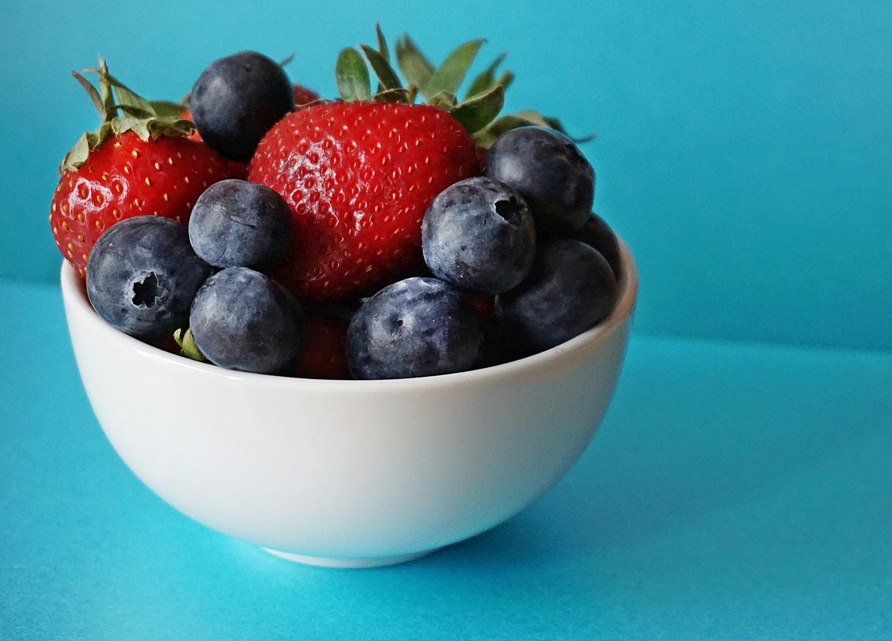 Dark Berries and Tooth Staining — Foods That Discolor Teeth Bowl of fresh strawberries and blueberries — colorful berries are among the top foods that stain teeth