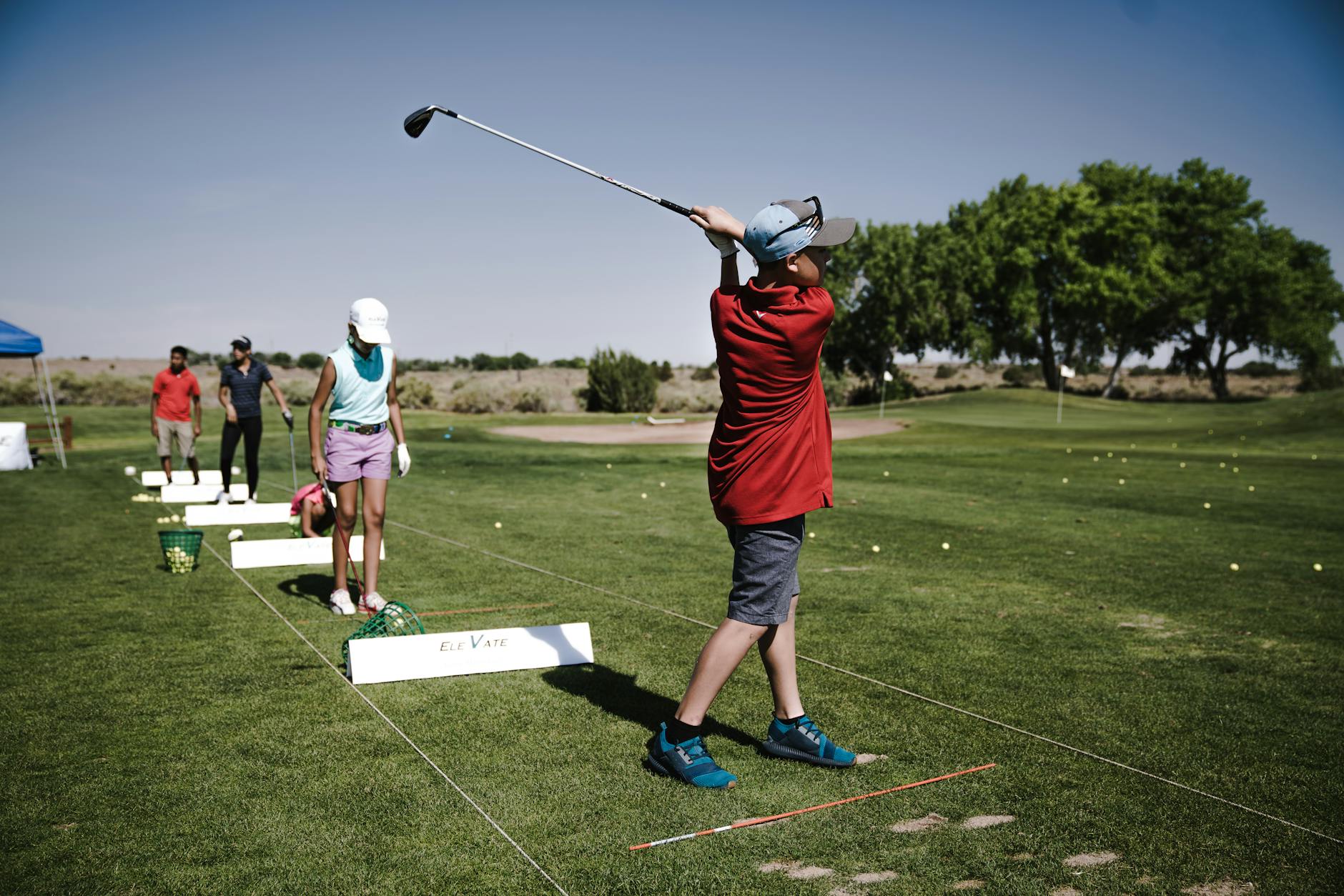 Golf Swing Training and Flexibility 2026 Youth golfers practicing swing technique at a driving range — flexibility is key to a repeatable swing