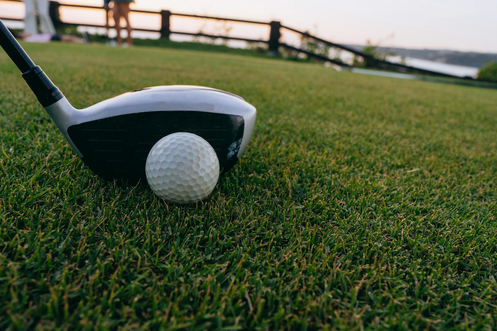 Golf Ball Setup at Sunset on the Course Golf ball and club on grass during sunset, illustrating tee shot setup