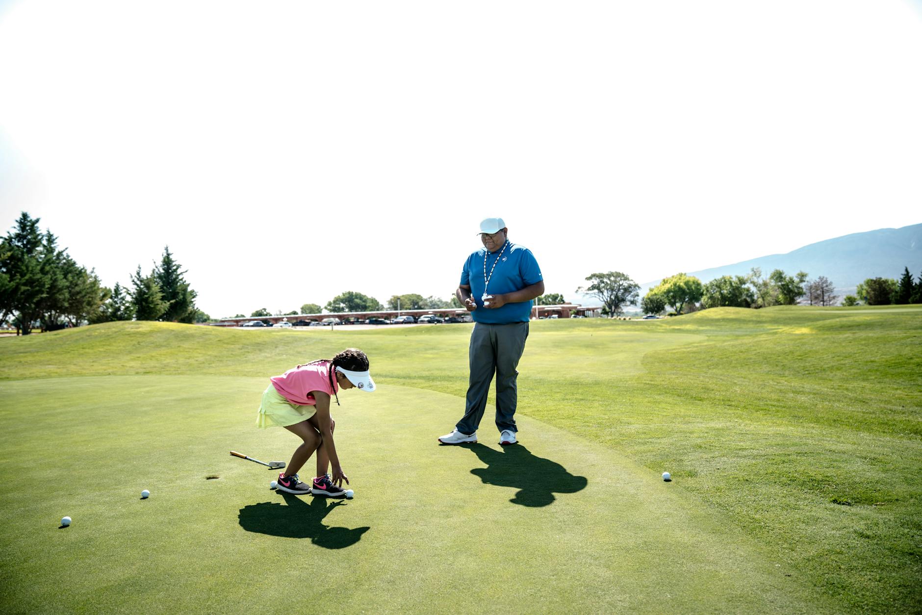Golf Beginner Learning to Play Golf instructor teaching a young beginner golfer on a sunny course