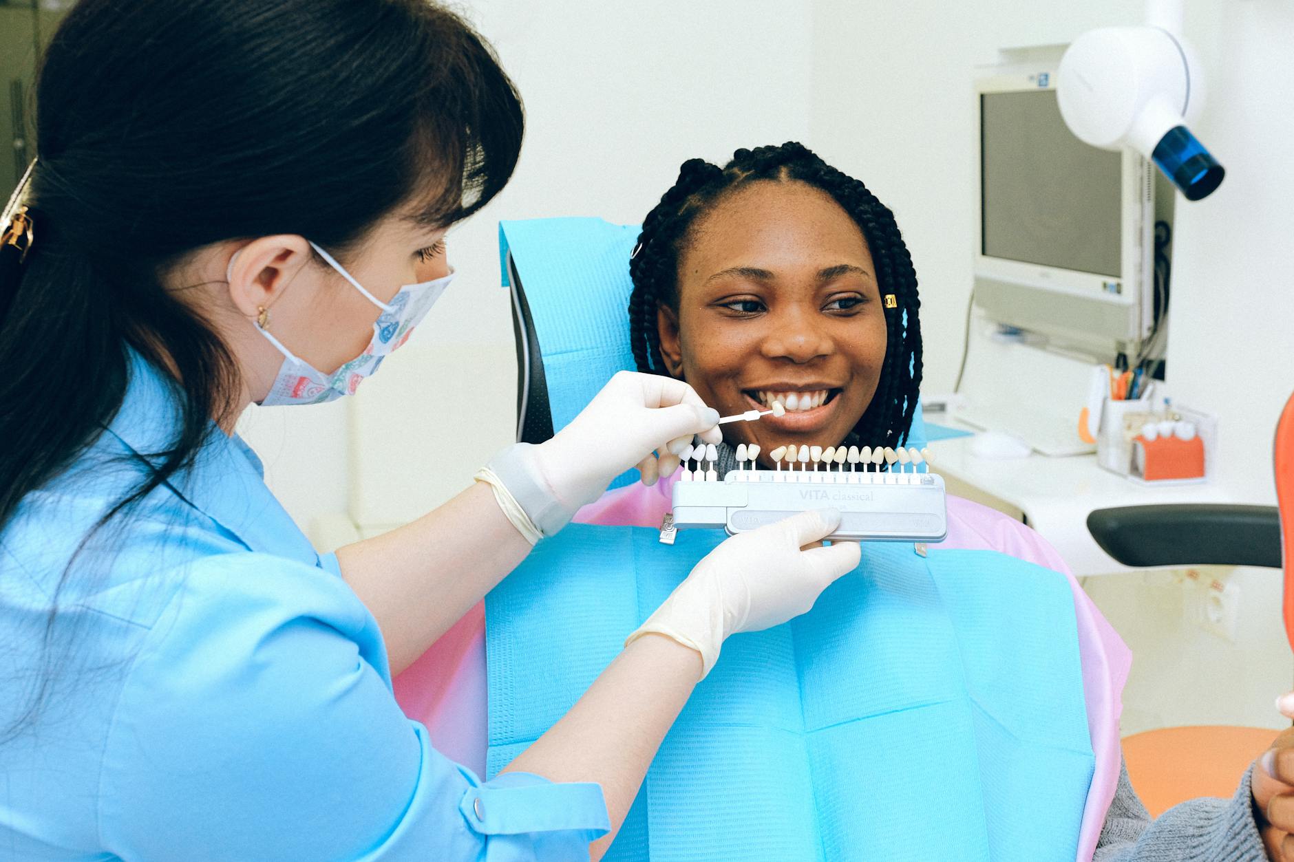 Dentist Consultation for Teeth Whitening Maintenance Plan Dentist consulting with patient using teeth color shade samples in a dental clinic