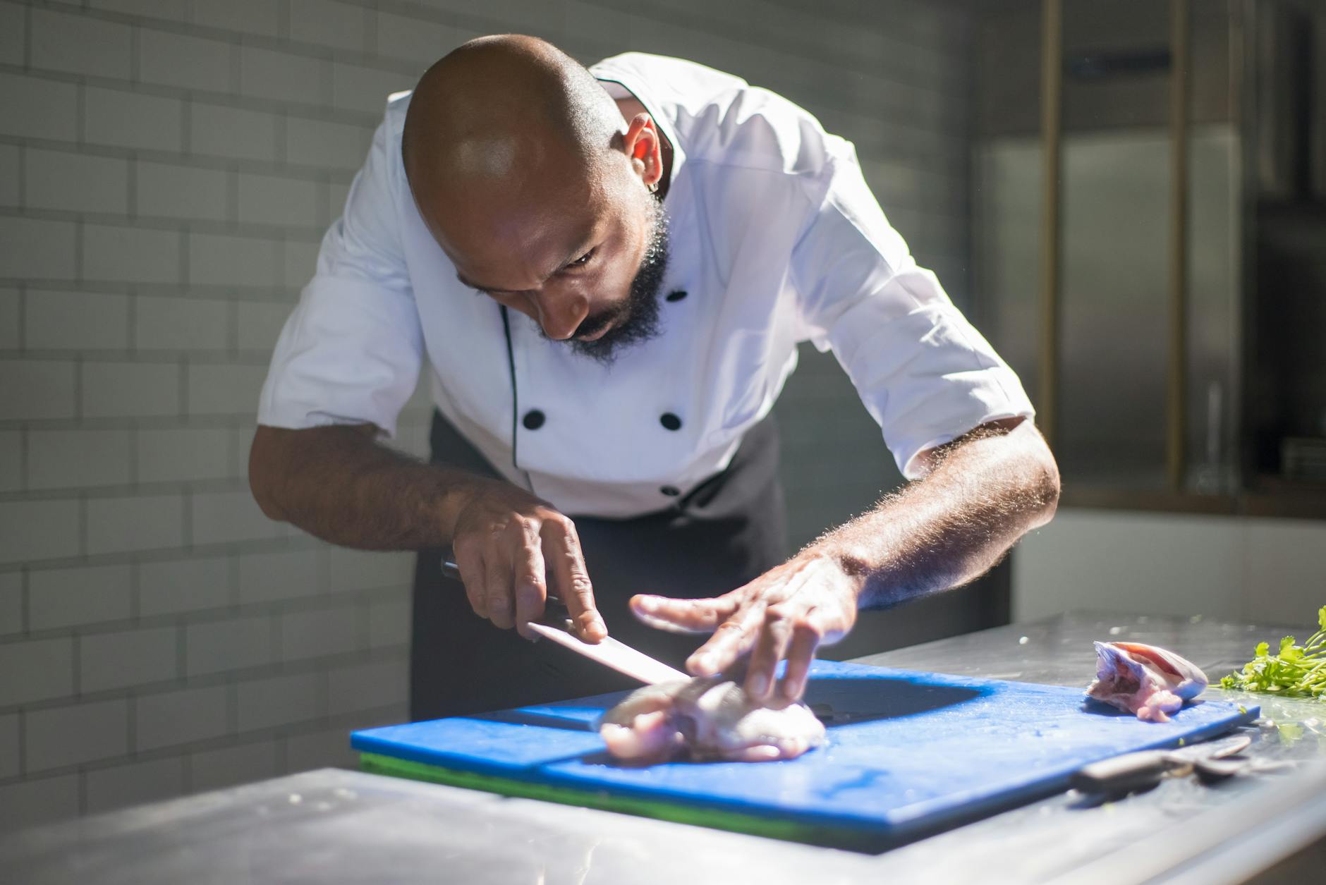 Using a Sharp Chef Knife on a Cutting Board Sharp chef knife being used on a wooden cutting board in a professional kitchen