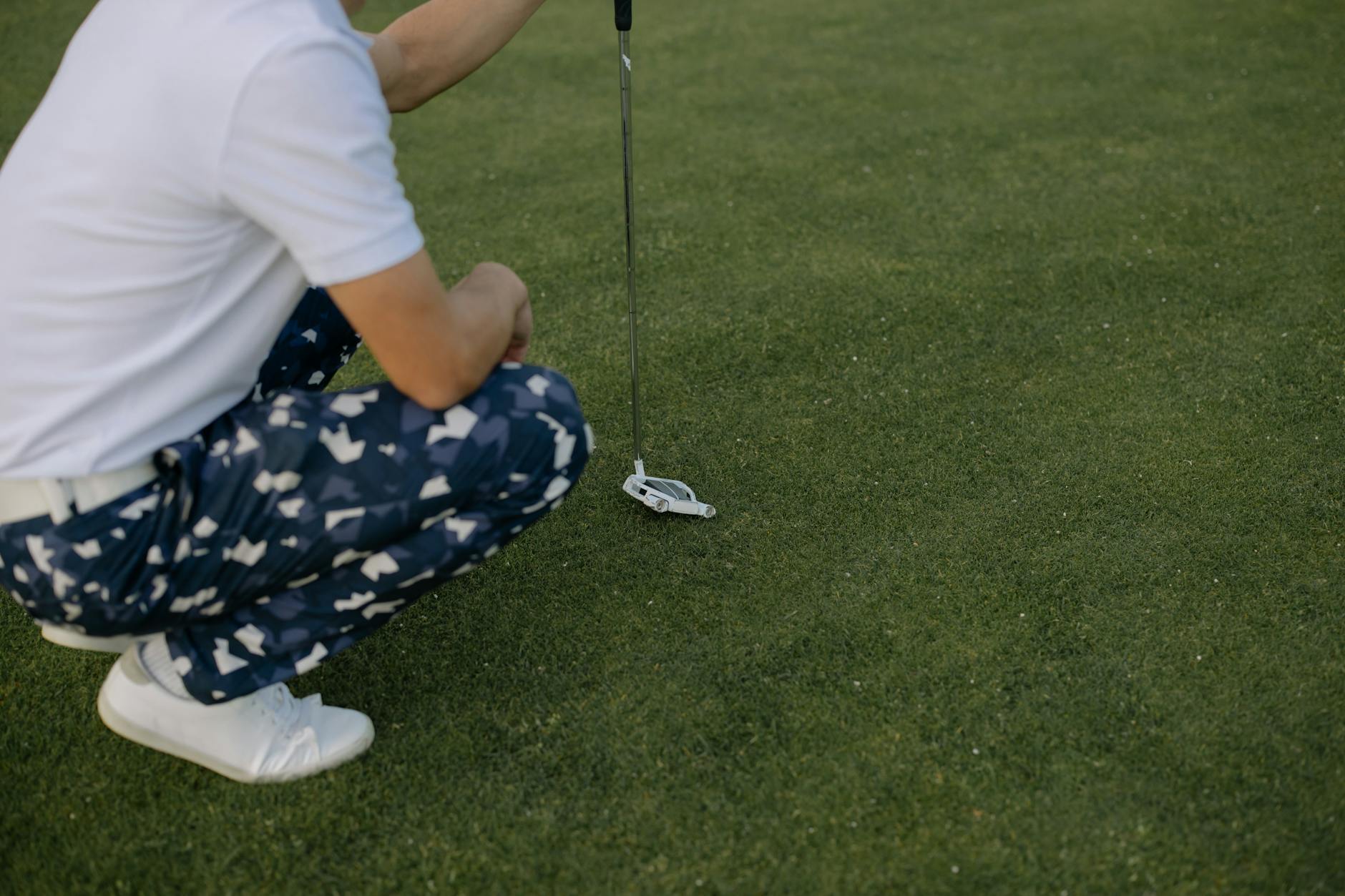 Reading the Green from the Low Side Golfer crouching on the green carefully studying the line before putting