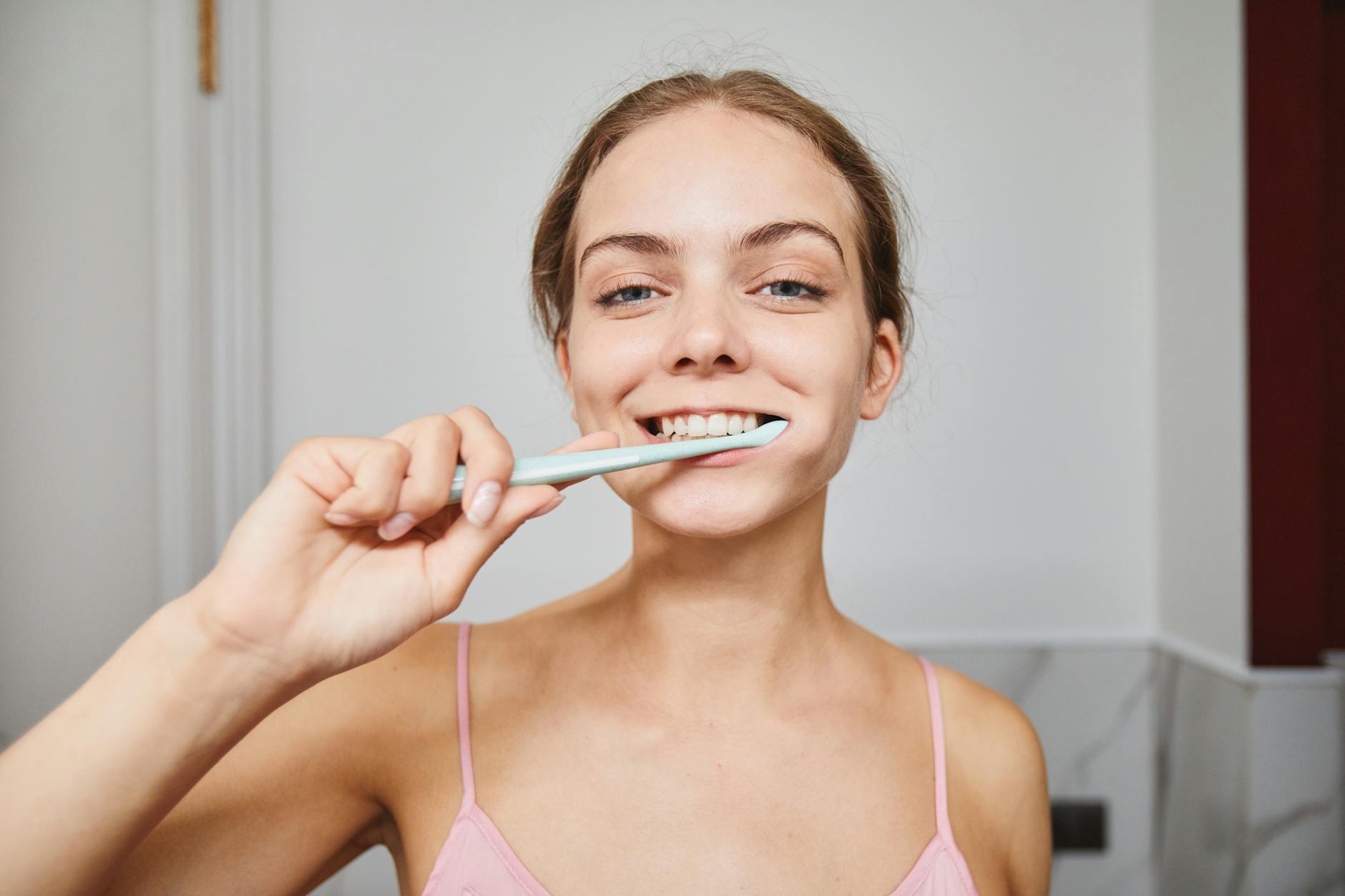 Daily Oral Hygiene Routine Supports Enamel Remineralization Woman brushing teeth with remineralizing toothpaste as part of daily oral hygiene routine