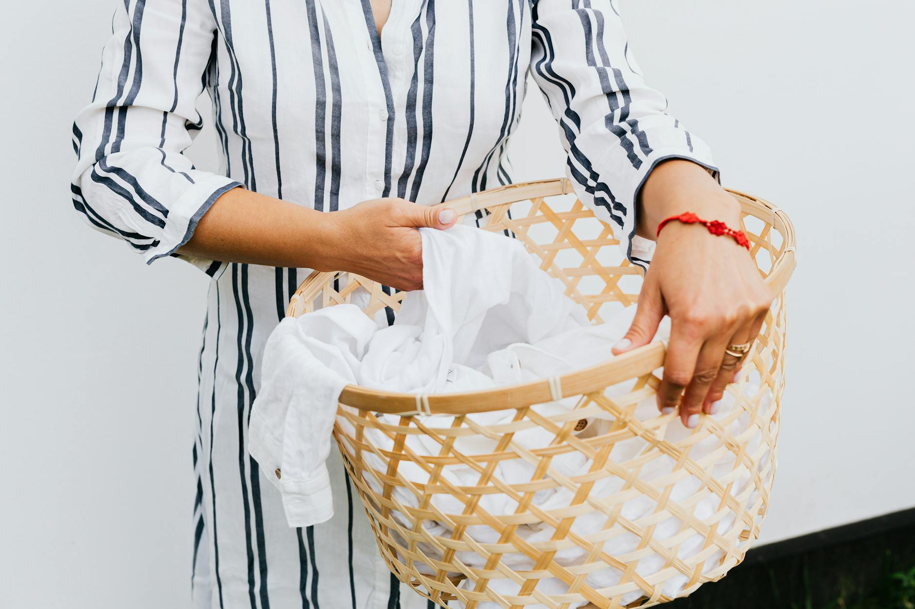 How to Do Laundry Correctly — Sorting and Loading Tips Woman carrying a laundry basket of white clothes ready to wash correctly