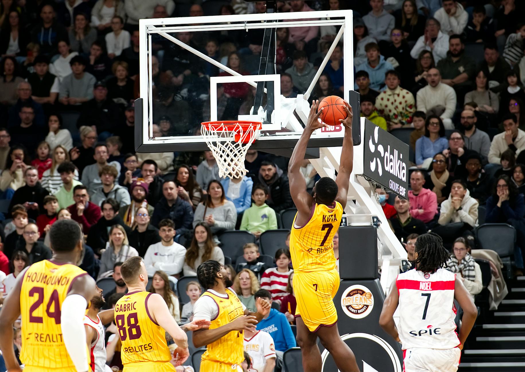 March Madness Tournament Game Action and Crowd 2026 A basketball player scores with a jump shot in front of a packed arena crowd during a tournament game