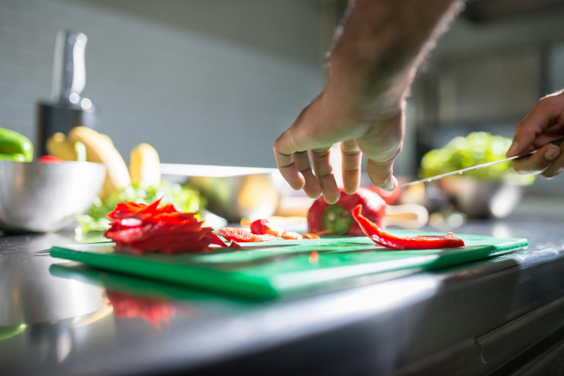 Slicing Vegetables Cutting Board Microplastics Hands slicing red bell pepper on a plastic chopping board — a common kitchen task that can release microplastic particles