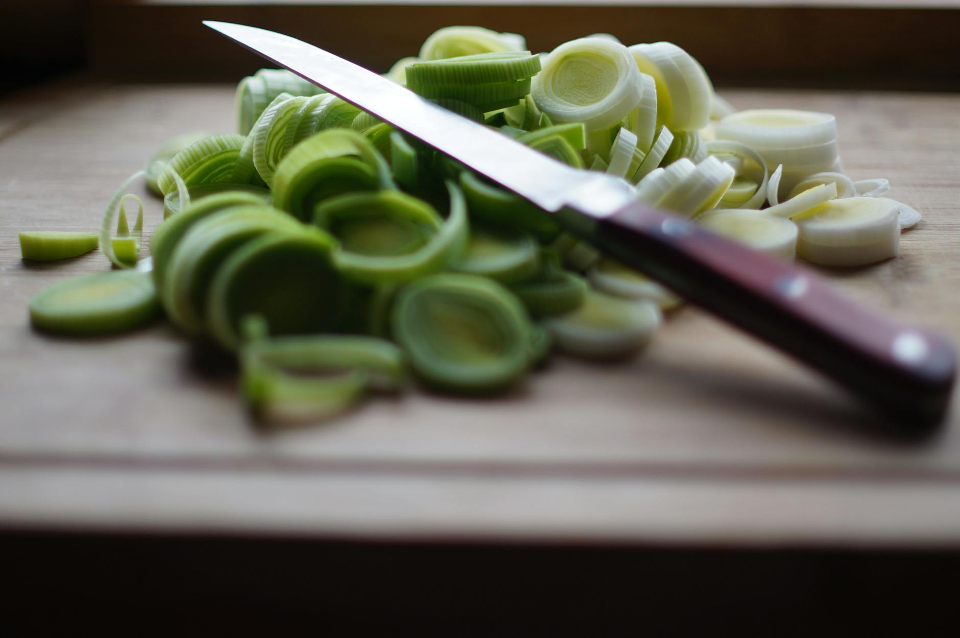 Wooden Cutting Board Food Safety Alternative Freshly sliced leeks on a wooden cutting board with a knife — a plastic-free cutting surface alternative