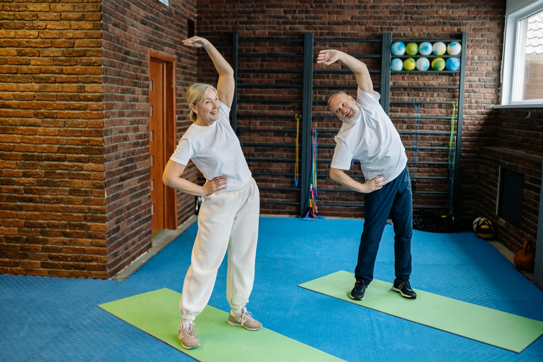 Senior Couple Stretching — Drug-Free Joint Pain Relief 2026 Elderly couple doing stretching exercises on yoga mats at home for joint pain relief