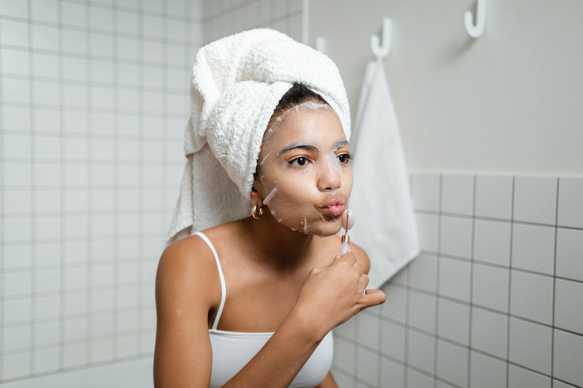 Woman skincare routine - managing PCOS skin Young woman applying skincare in a bathroom as part of her self-care routine