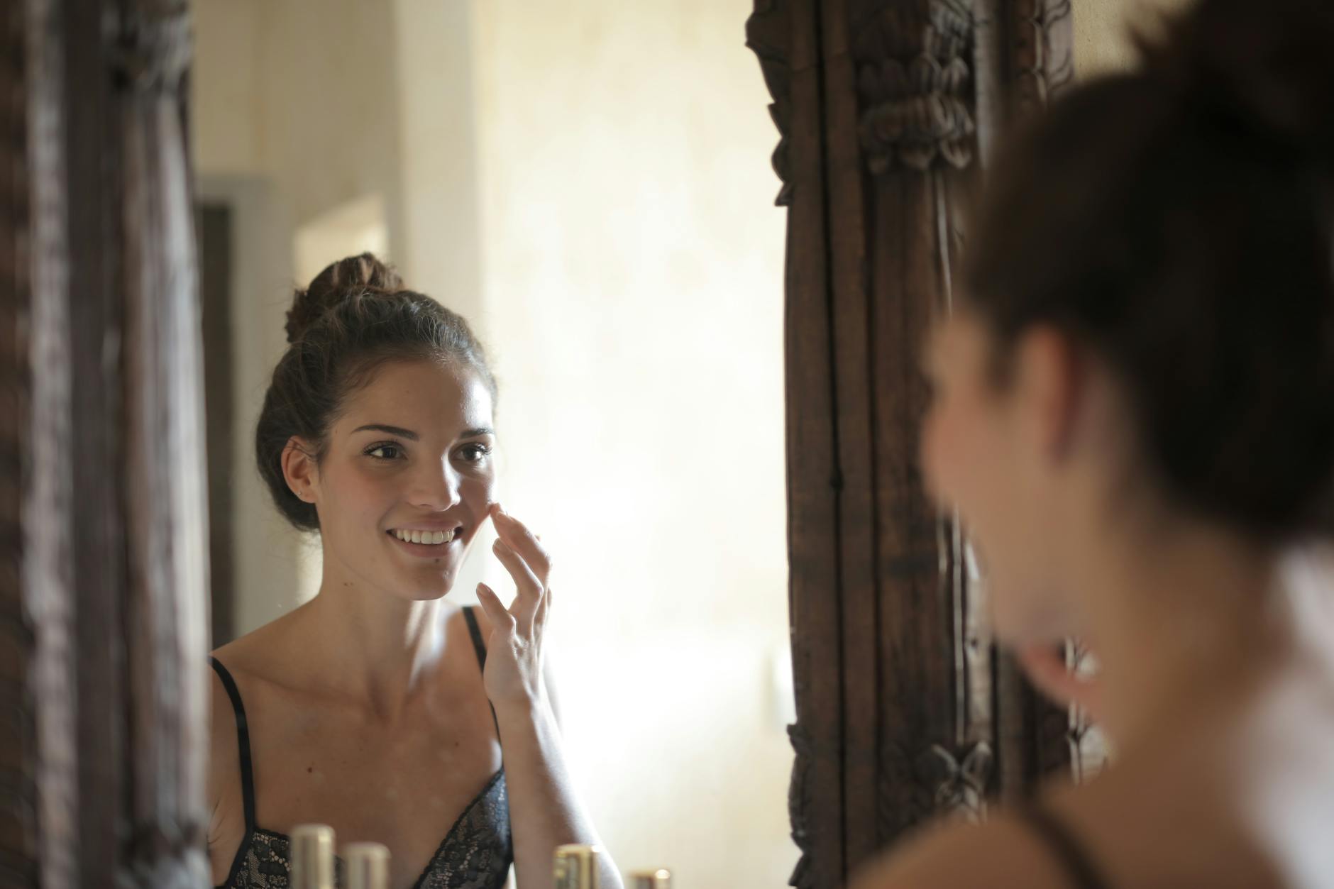 Woman looking in mirror - PCOS self-care and confidence Young woman looking confidently at her reflection in a mirror