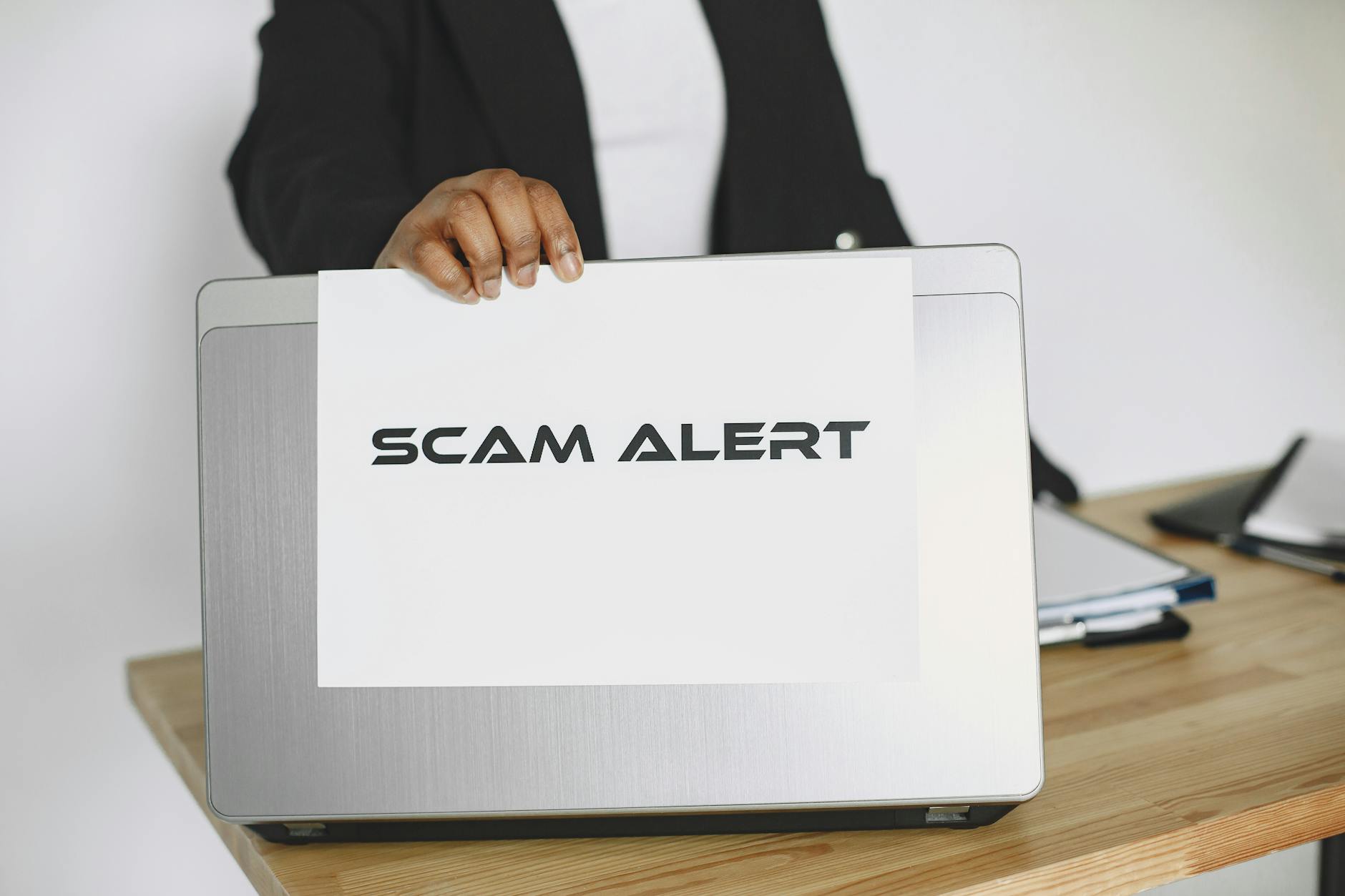 Recognizing Online Scams and Phishing Fraud 2026 Person holding a scam alert sign over a laptop, illustrating online fraud awareness