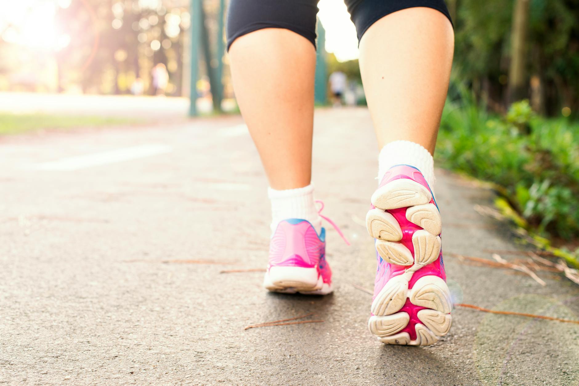 Walking for Leg Circulation Improvement 2026 Woman walking outdoors in pink sneakers — regular walking is one of the best leg circulation exercises