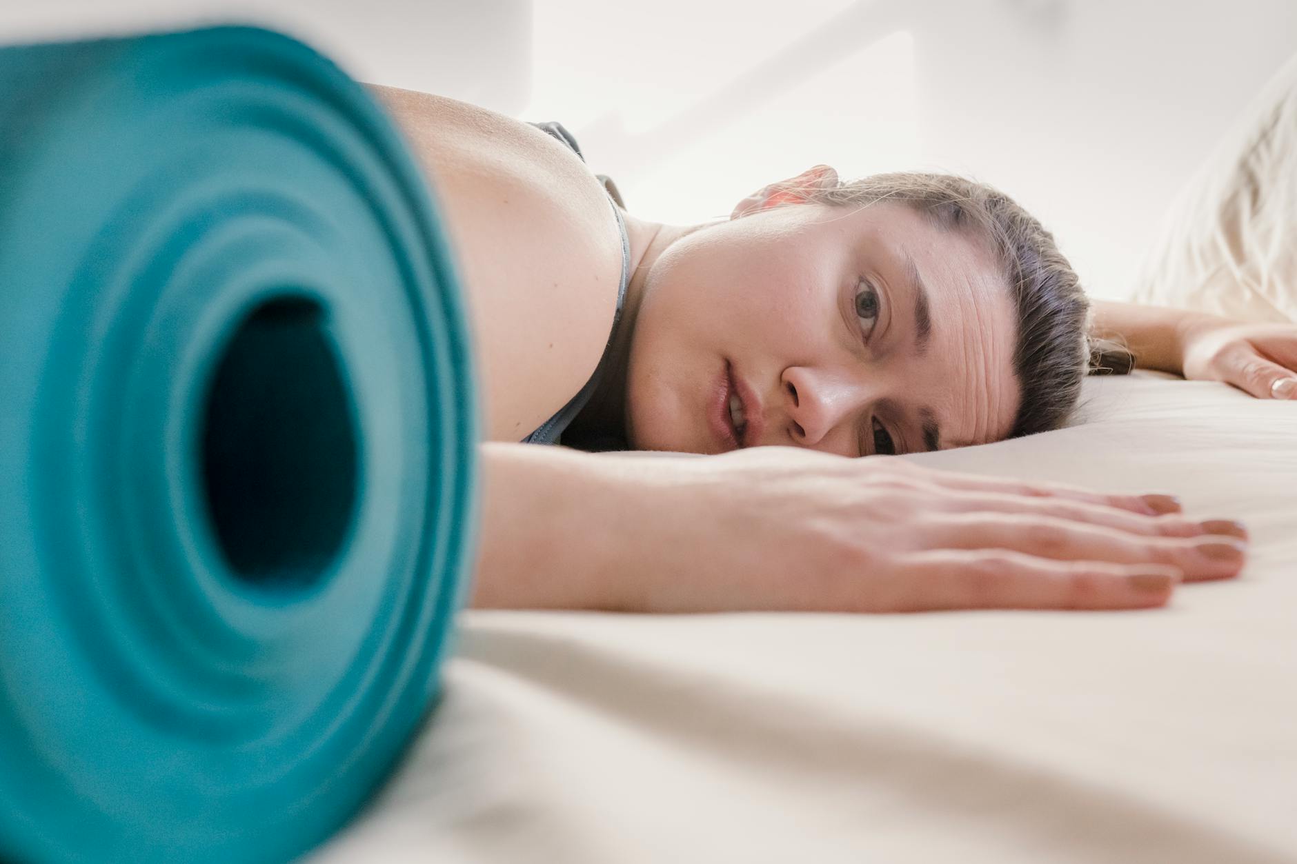 Post-Exercise Rest and Recovery Woman resting after exercise near a yoga mat, illustrating post-workout recovery