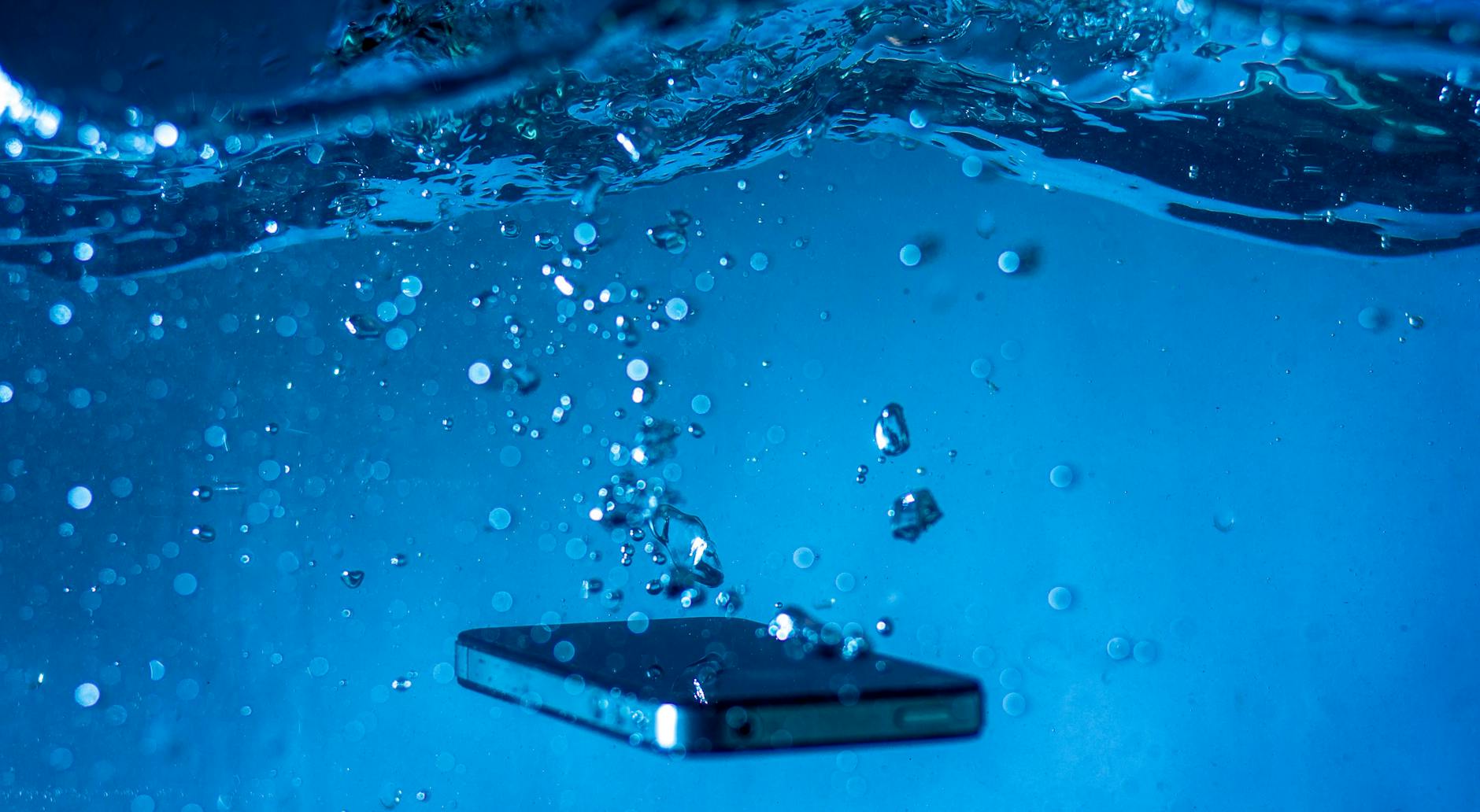 Water Damage Is a Leading Cause of Photo Loss Smartphone submerged in water, illustrating the risk of water damage to devices carrying irreplaceable photos