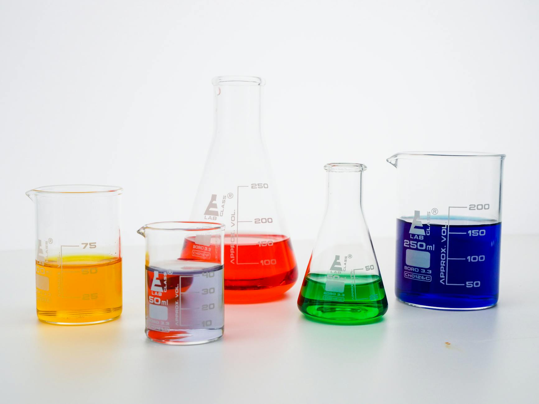 Laboratory Chemistry Research on Whitening Compounds 2026 Colored liquid solutions in laboratory beakers representing chemical whitening ingredient research