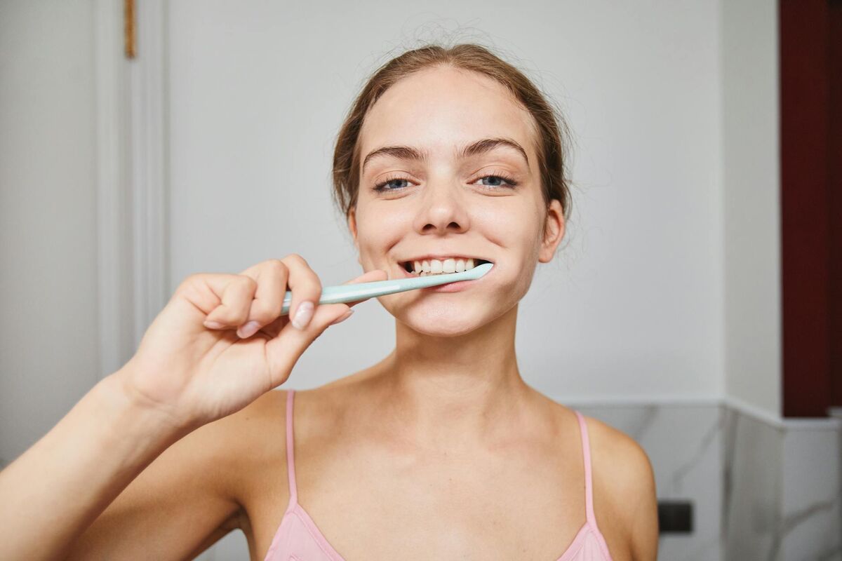 Consistent Oral Care Routine for Whitening Results Close-up of a woman smiling while brushing her teeth in a modern bathroom