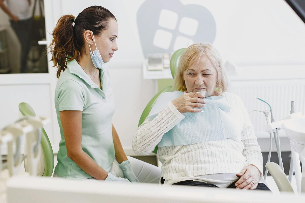 Dental Consultation for Aging Teeth Discoloration Treatment Dentist consulting with a senior female patient in a dental clinic